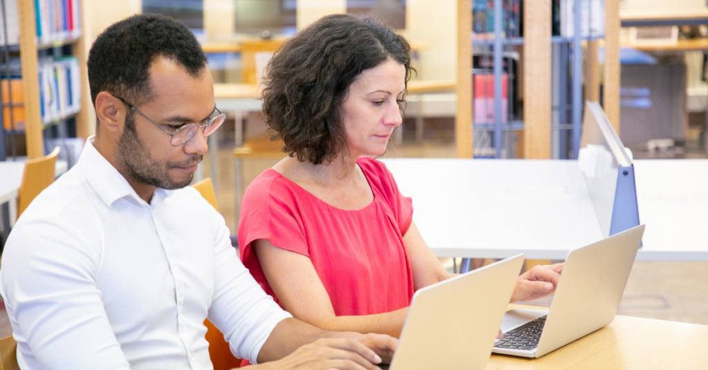 two people learning in the library with their laptop