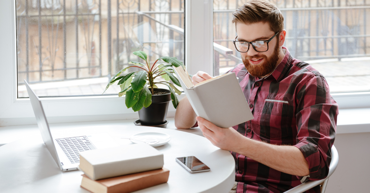 man wearing red and black shirt reading a book